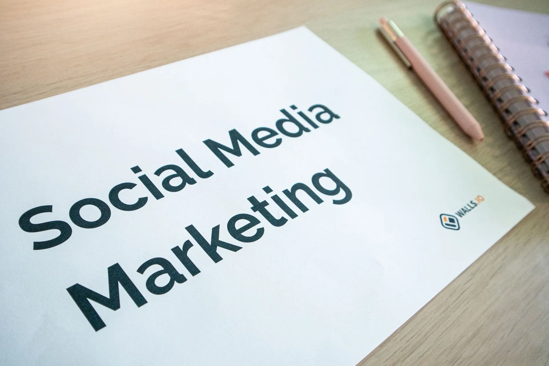Folha com o título Social Media Marketing pousada numa secretária de madeira
