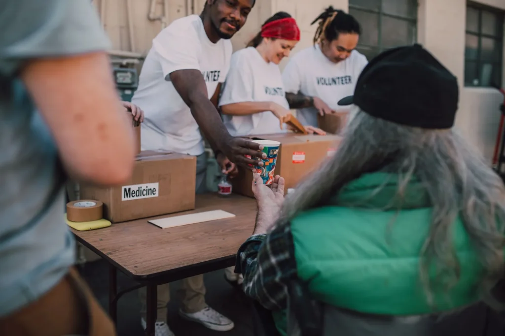 Voluntários a organizar caixas de donativos numa mesa e a falar com uma pessoa da comunidade