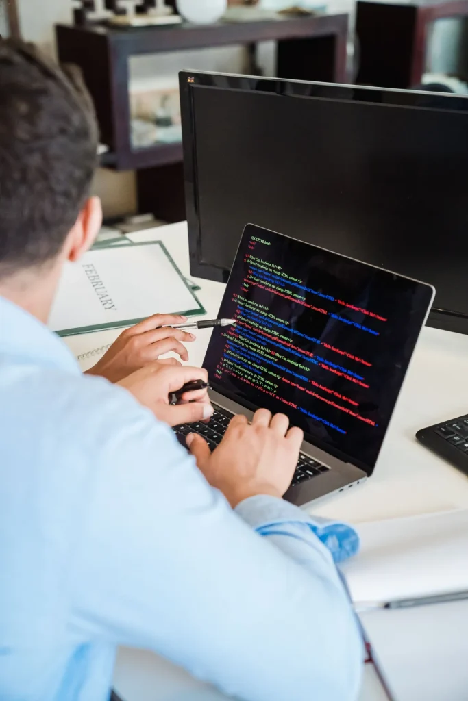 Programador a escrever código num portátil, com um segundo monitor ao lado